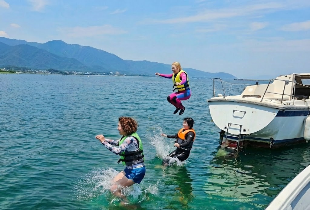 琵琶湖のヨットサウナからライフジャケットを着用して天然の水風呂へダイブする女性グループ